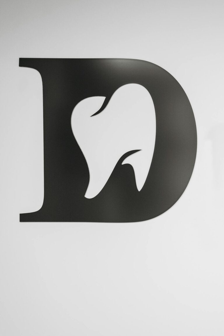 Simple black and white tooth design within letter D, ideal for dental branding.